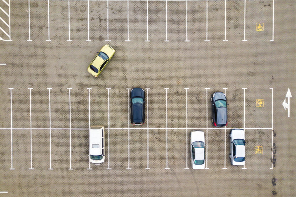 Aerial view of a nearly empty parking lot with a few parked cars, illustrating the demand for rental vehicles during the busy Black Friday travel season.