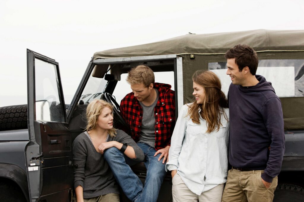 A group of friends stopping to talk on the road in their car.